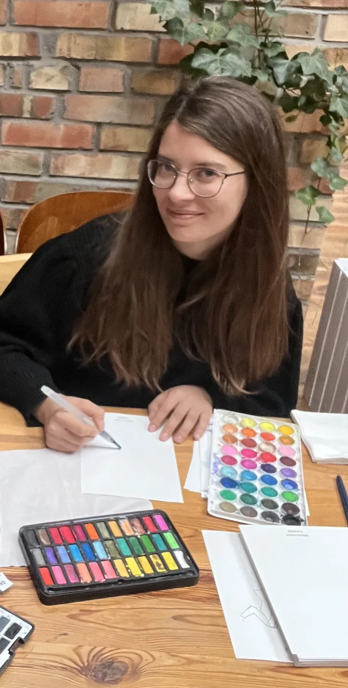 Ilustratorka przy pracy nad akwarelowym portretem goscia
