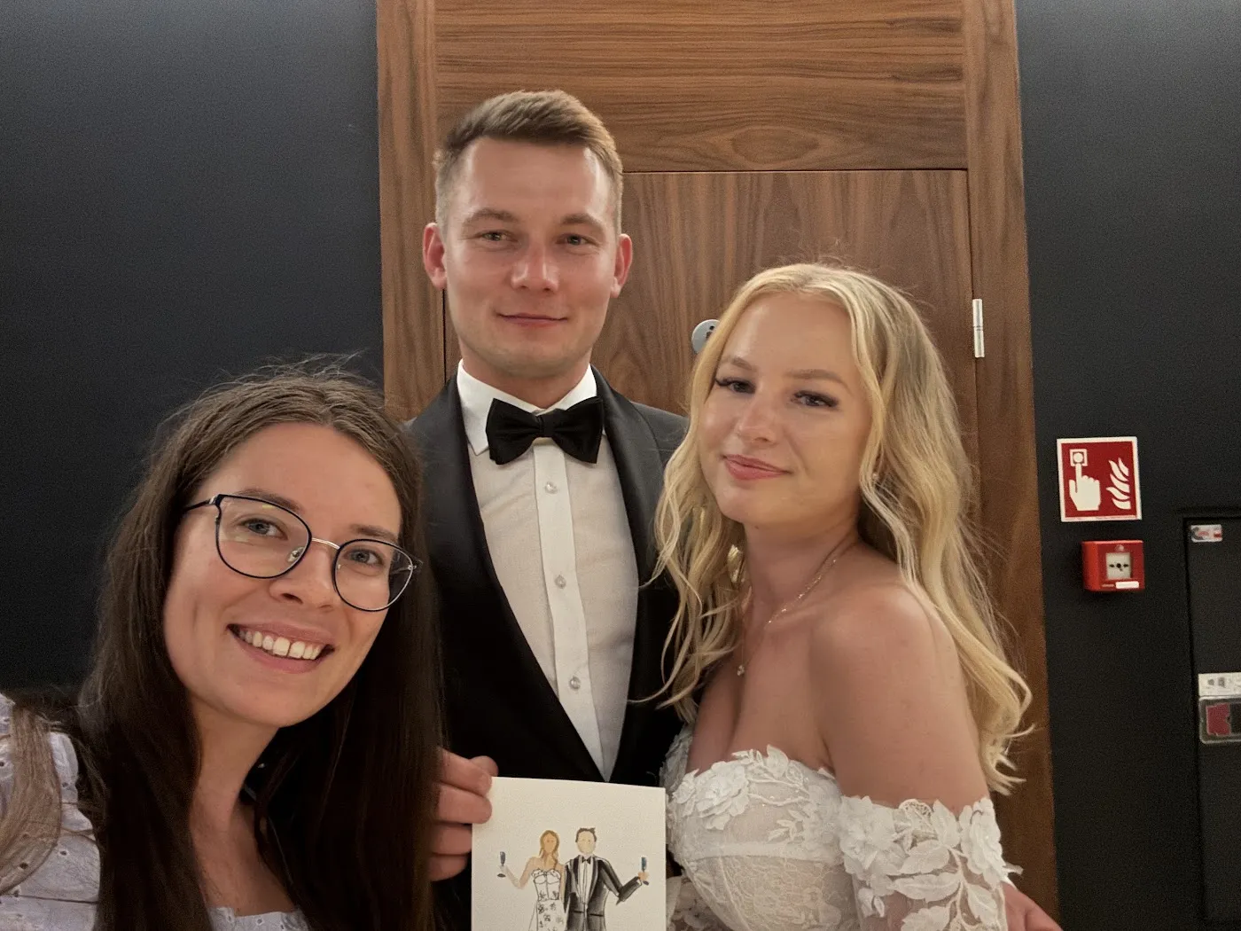 Artystka robi zdjęcie z parą młodą trzymającą ich akwarelowy portret