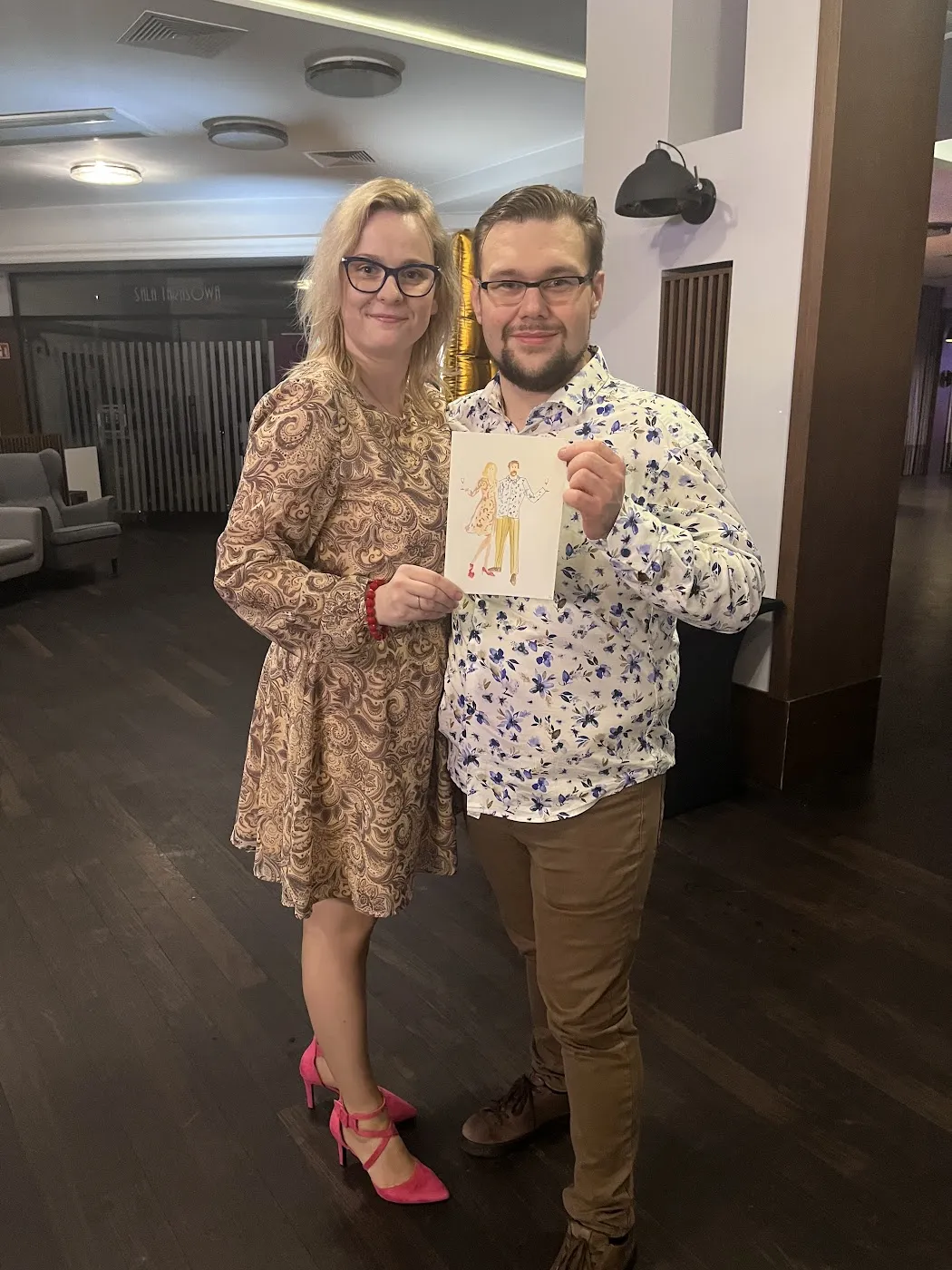 Para gości pokazuje swój akwarelowy portret na sali w Kolumna Park
