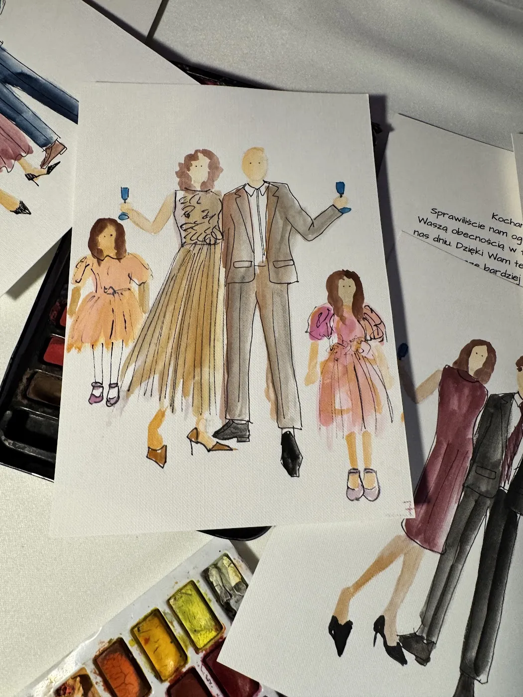 Akwarelowa ilustracja rodziny z dwiema dziewczynkami obok farb