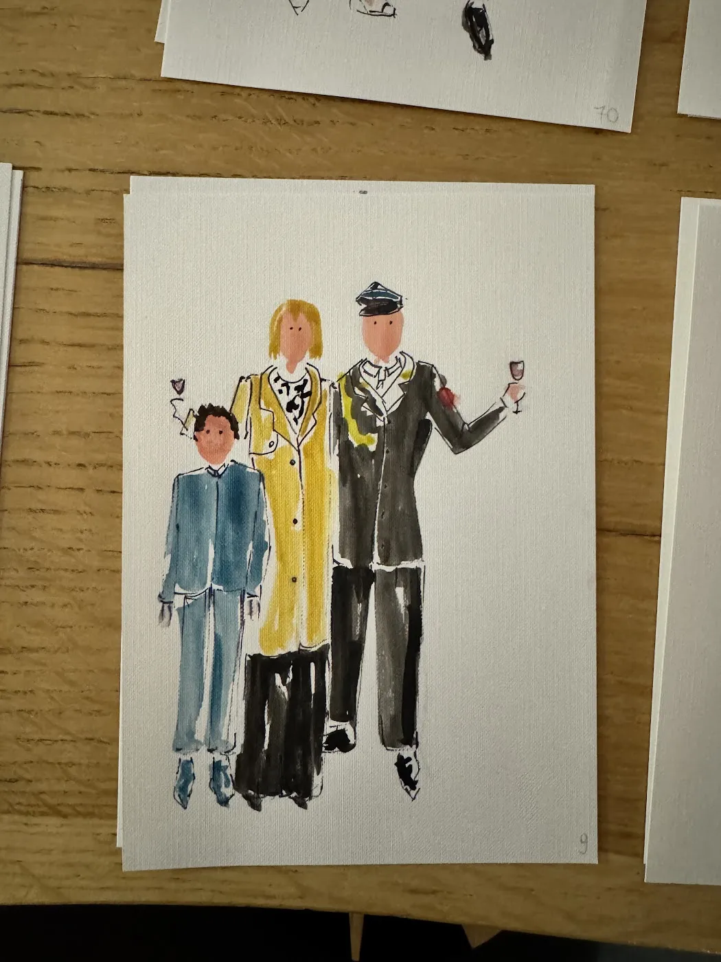 Akwarelowa ilustracja rodziny z dzieckiem na drewnianym stole z farbami
