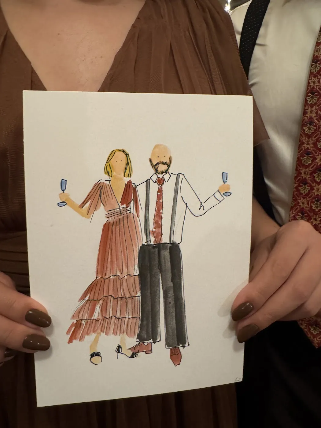 Gość trzyma akwarelową ilustrację pary w stylowych strojach