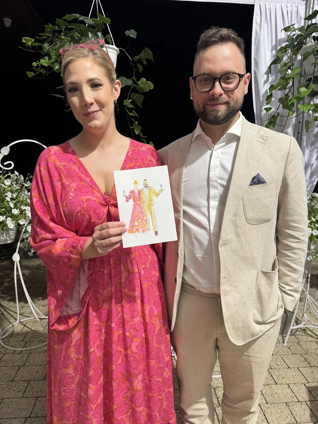 Para gości trzyma swój akwarelowy portret na dziedzińcu Patio Zajazd