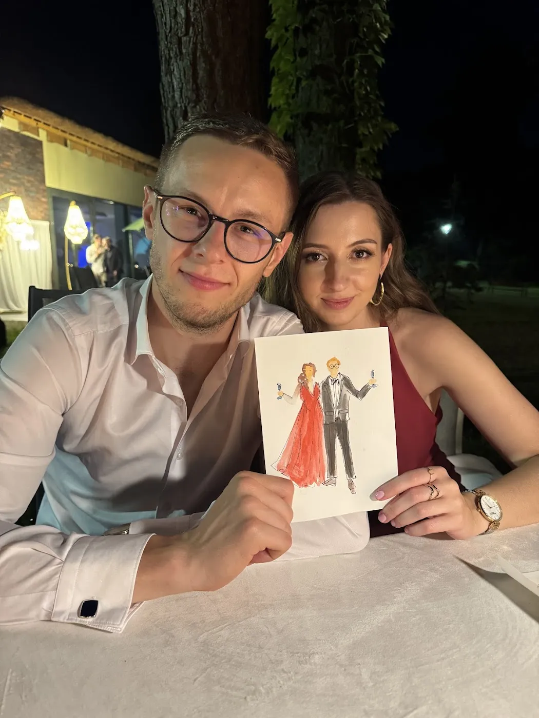 Para gości przy stole weselnym prezentuje swoją akwarelową ilustrację