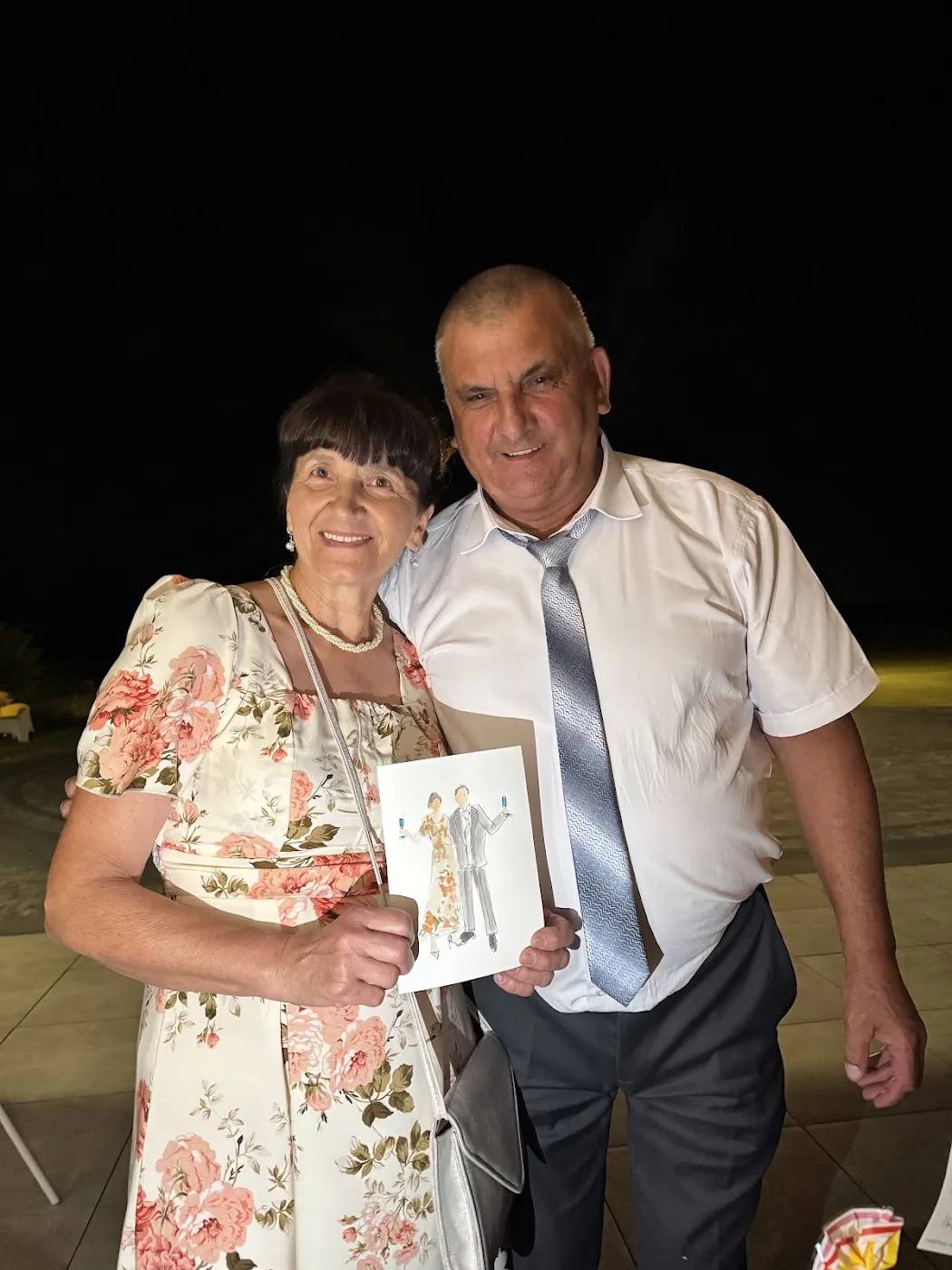 Starsza para gości pokazuje swój akwarelowy portret na weselu