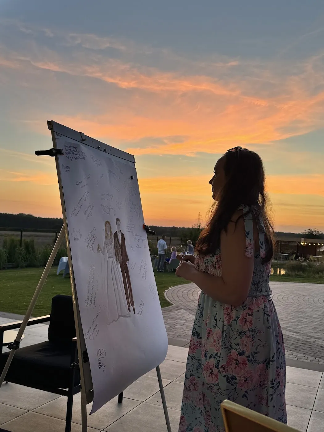 Ilustracja pary młodej z życzeniami gości na sztaludze o zachodzie słońca