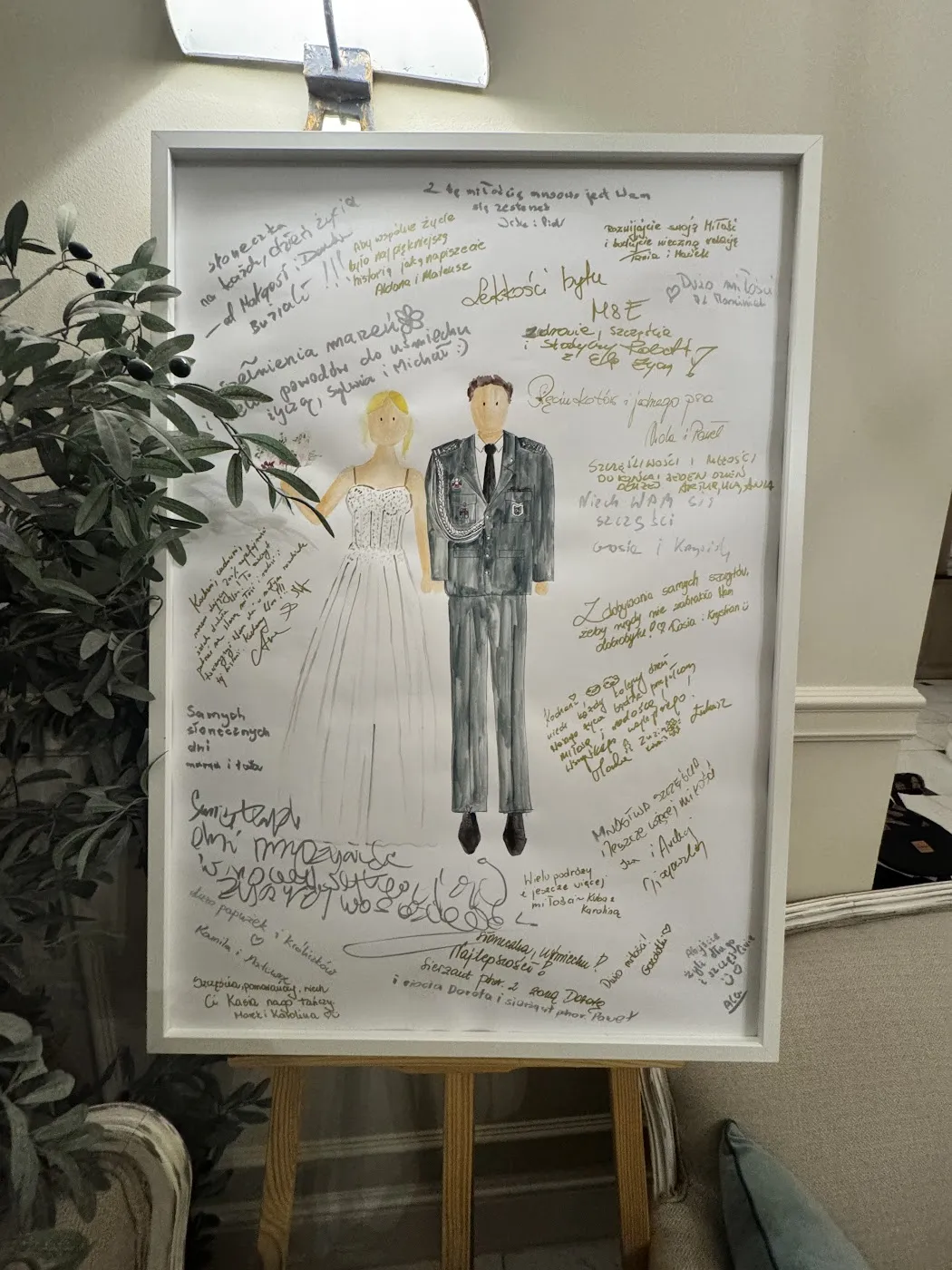 Ilustracja pary młodej w ramie z wpisami gości na sztaludze