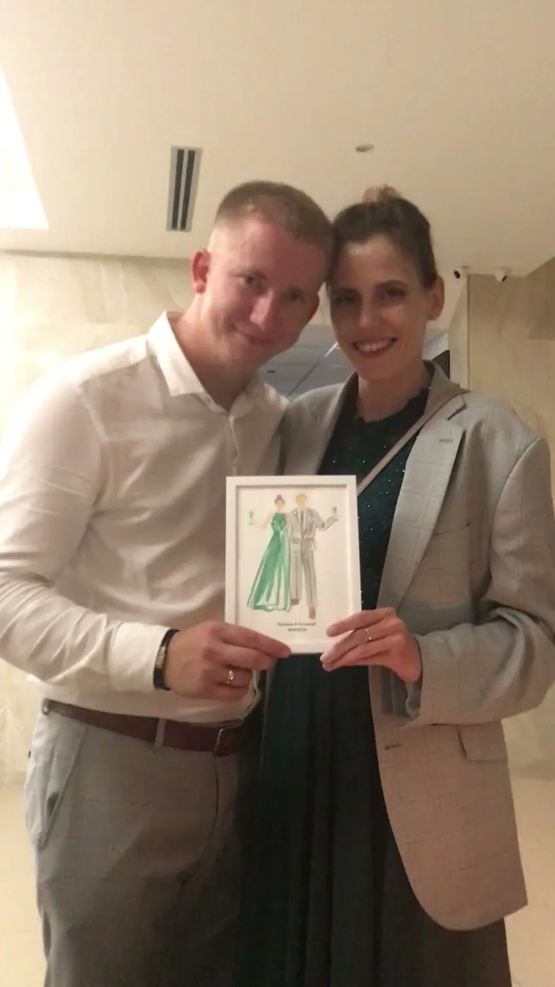 Uśmiechnięta para trzyma akwarelową ilustrację podczas wesela w Panoramie Tucholi