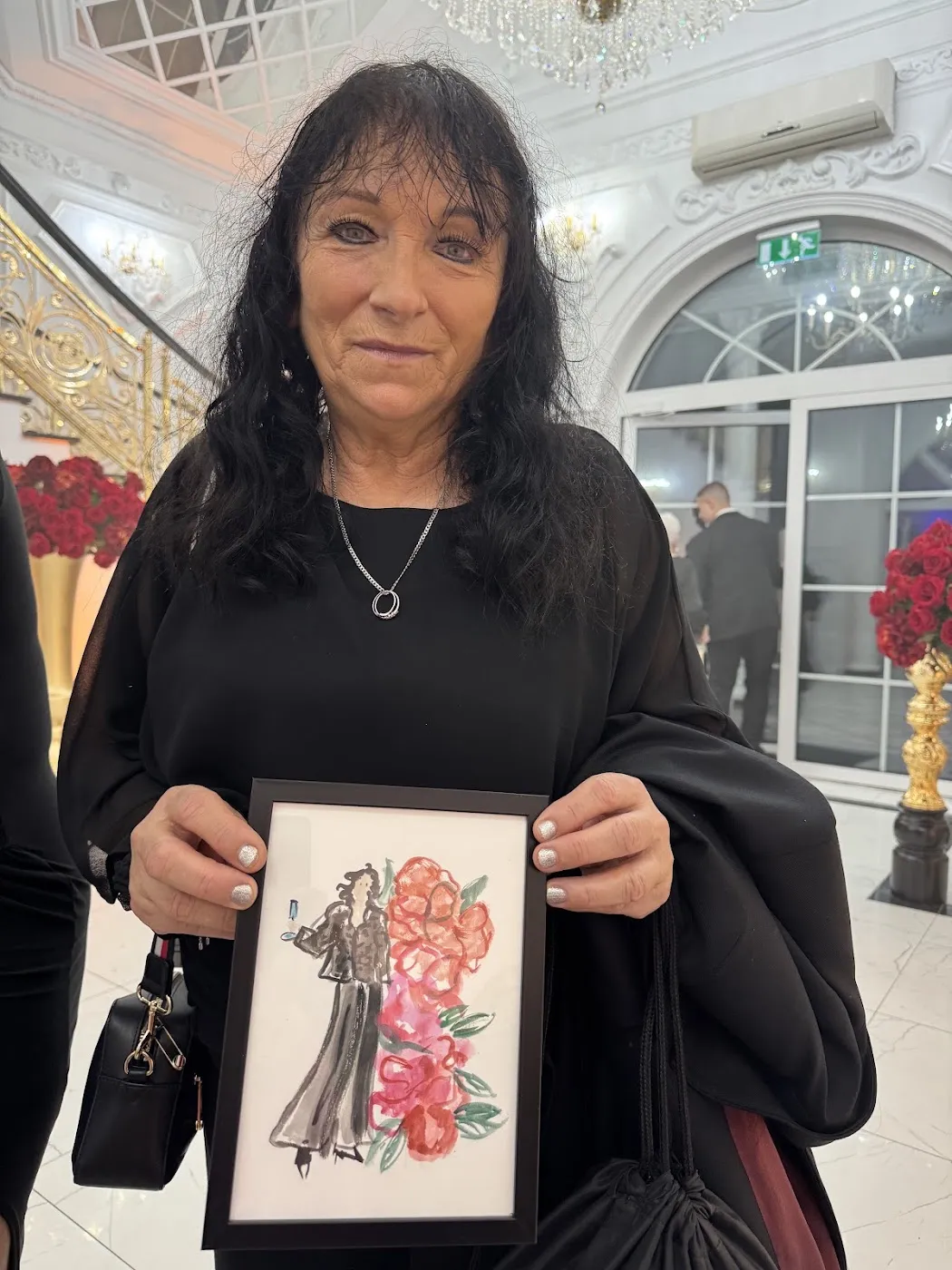 Uśmiechnięta kobieta trzyma oprawioną akwarelową ilustrację jako pamiątkę z wesela